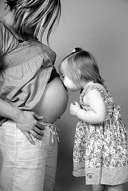 Toddler kissing pregnant woman's belly