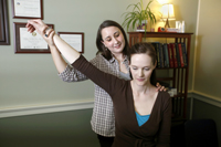 photo of a female doctor holding up the arm of a seated patient