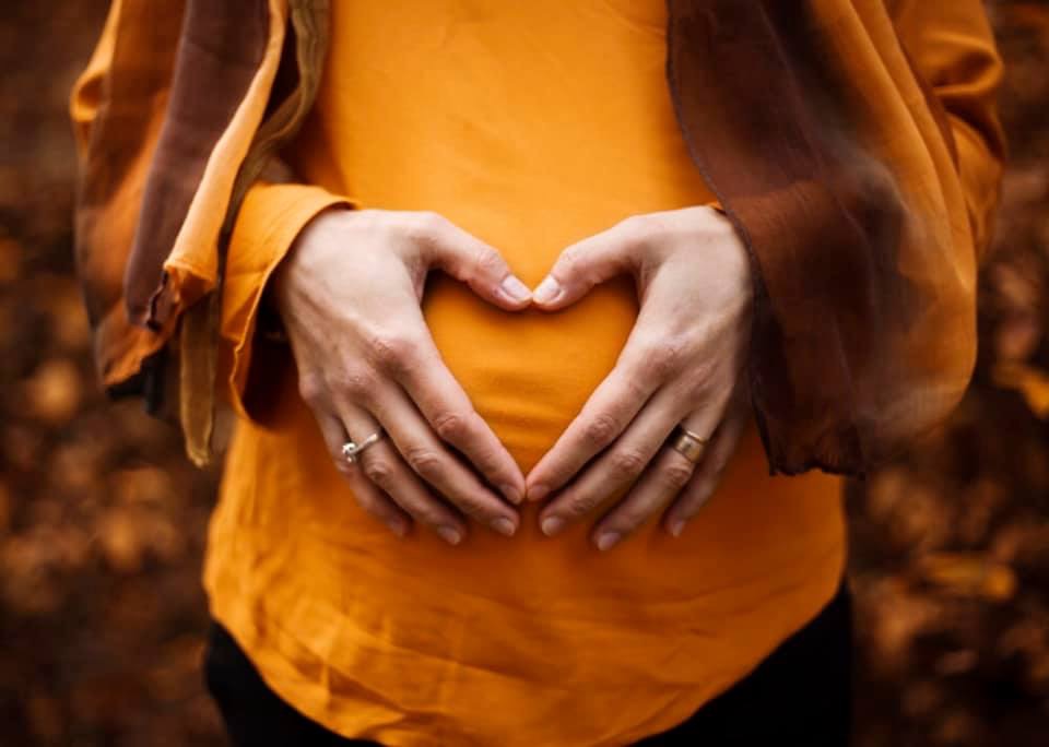 Pregnant belly with heart hands